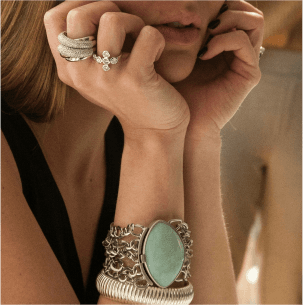 Black and white image of a hand wearing multiple rings and a bracelet